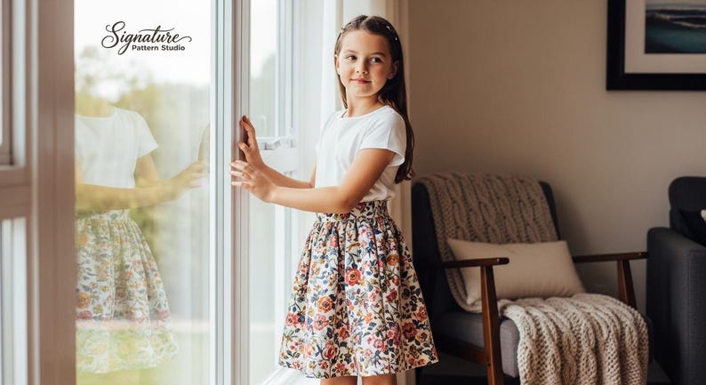 May include: A young person wearing a white t-shirt and a floral print skirt stands near a window. The skirt features a pattern of red, pink, and yellow flowers. The text "Signature Pattern Studio" is visible in the upper left corner.