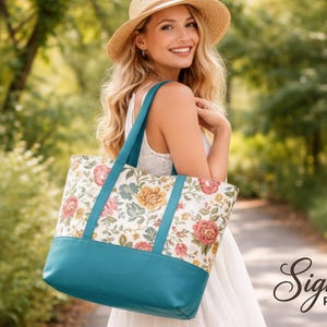 May include: A tote bag with a floral pattern and teal blue base and straps. The bag has a cream background with red, yellow, and pink flowers. The words "Signature Pattern Studio" are in the bottom right corner.