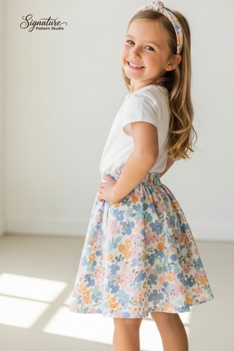 May include: A young girl wearing a white t-shirt and a floral skirt. The skirt features a pattern of blue, pink, and yellow flowers on a white background. A floral headband complements the outfit. The text "Signature Pattern Studio" is in the upper left corner.