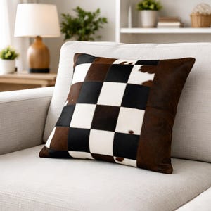 May include: A white ceramic mug with a black handle and the text "But First, Coffee" in a bold, black font. The mug is set against a blurred background, suggesting a cosy setting.