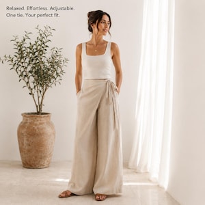 Puede incluir: Una camiseta sin mangas de color beige y pantalones anchos cruzados a juego con un cierre de lazo lateral. El texto en la imagen dice: Relaxed. Effortless. Adjustable. One tie. Your perfect fit. El conjunto es de color claro y sencillo.