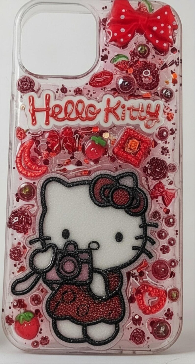 Puede incluir: Funda de tel&eacute;fono transparente con un dise&ntilde;o rosa y rojo que presenta a Hello Kitty sosteniendo una c&aacute;mara. La funda est&aacute; decorada con lazos rojos, fresas y purpurina. Las palabras "Hello Kitty" son rojas.