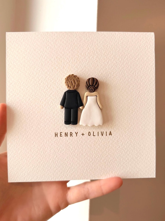 A real maker sculpts tiny clay likenesses of the actual couple — hair color, skin tone and all — making this a genuinely one-of-a-kind keepsake card no algorithm can replicate.