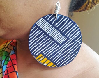 May include: Large round blue and white patterned earrings with a yellow accent. The earrings are made of wood and have a silver wire hanger.