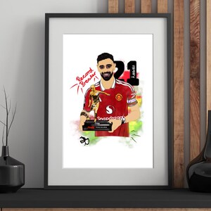 Pode incluir: Uma ilustração digital emoldurada de um jogador de futebol com a camisola vermelha do Manchester United a segurar um troféu dourado. A obra apresenta o texto Record Breaker, o número 21 e a palavra Assists num fundo branco com detalhes coloridos.