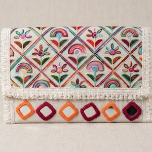 Può includere: Pochette color crema con ricami floreali e arcobaleno colorati. La patta e il bordo inferiore presentano finiture in crochet decorative. Il bordo inferiore presenta accenti quadrati arancioni e bordeaux alternati.