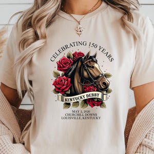 May include: Beige t-shirt featuring a horse head design with red roses and the text "Celebrating 150 Years Kentucky Derby". Additional text includes "May 2, 2026 Churchill Downs Louisville, Kentucky".