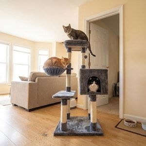 May include: A multi-level cat tree with three cats. The tree has a gray base, posts wrapped in beige rope, and platforms. One cat sits on top, another in a basket, and a third in a cubby.