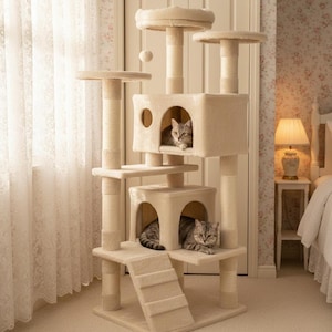 May include: A beige cat tree with multiple platforms, scratching posts, and enclosed cat houses. Two tabby cats are resting inside the cat tree. A small hanging ball is attached to the top. The cat tree is made of soft, plush material.