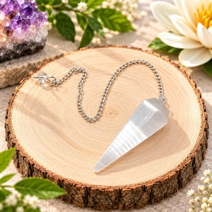 Op de afbeelding: Een heldere, gefacetteerde en puntige kristallen pendel bevestigd aan een zilverkleurige metalen ketting. Het kristal heeft een glad, doorschijnend uiterlijk met een taps toelopende vorm en de ketting heeft een kleine ring aan het uiteinde.