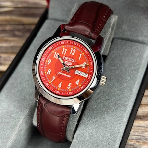 Reloj de pulsera automático Seiko 5 vintage restaurado, esfera roja, ventana de fecha y día, en perfecto estado de funcionamiento.