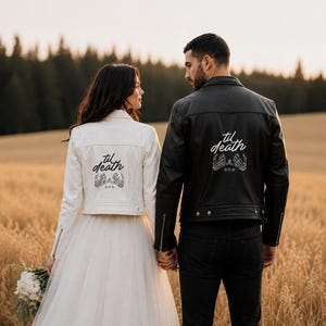 May include: A white leather jacket and a black leather jacket, each featuring the text 'til death' in white script above a graphic of two skeleton hands making a pinky promise, with the date 10-19-26 printed below the hands on both jackets.