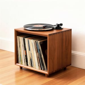 Puede incluir: Una taza de cerámica blanca con un asa negra y el texto "But First, Coffee" en negrita negra. La taza está sobre un fondo borroso, sugiriendo un ambiente acogedor. La taza mide aproximadamente 10 cm de altura.