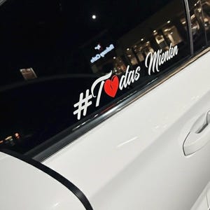 May include: White car window decal with the text "#Todas Mienten" in white script, a red broken heart graphic, and the words "Todas Mienten" in white script.