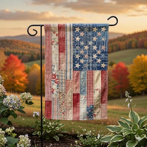 May include: A decorative garden flag featuring a patchwork design of the American flag. The flag has red and white stripes, a blue field with white stars, and is displayed on a black metal stand. The flag is made of fabric.
