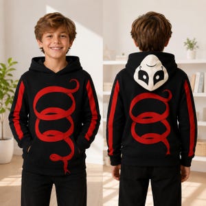 Puede incluir: Una sudadera negra con capucha que presenta un gran gráfico de serpiente roja enroscada en la parte delantera y trasera. Las mangas tienen rayas laterales rojas y el interior de la capucha muestra un diseño de máscara blanca con detalles.