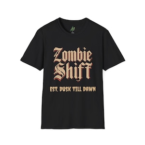 May include: Black t-shirt with the words "Zombie Shift" in a vintage font, with the text "EST. DUSK TILL DAWN" below. The shirt has a crew neck and short sleeves. The shirt is made of a soft material.