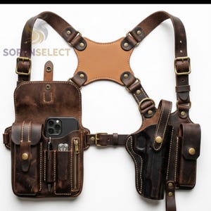 May include: A brown leather shoulder holster with multiple compartments, including a phone pocket, pen holder, and a holster for a firearm. The holster features adjustable straps, metal buckles, and a tan leather back panel.