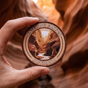 May include: A circular embroidered patch featuring a detailed landscape of Antelope Canyon, Arizona. The design includes shades of brown, tan, and white thread, with the text ANTELOPE CANYON and ARIZONA stitched in a tan border around the center.