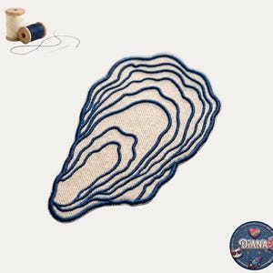 May include: An embroidered oyster patch with a cream-colored background and navy blue stitching. The patch is in the shape of an oyster shell. A spool of thread and a needle are in the upper left corner. A small circular patch with the name "DIANA" is in the lower right corner.