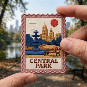 May include: A rectangular embroidered patch with a scalloped pink border, featuring a Central Park scene with a blue fountain, a brown park bench, a squirrel, tan buildings, and a red sun. The text CENTRAL PARK is stitched in brown at the bottom.