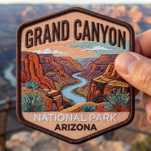 May include: A hexagonal embroidered patch featuring a landscape of the Grand Canyon with a winding blue river, red rock formations, and green desert shrubs. The text GRAND CANYON is at the top, with NATIONAL PARK ARIZONA printed at the bottom.