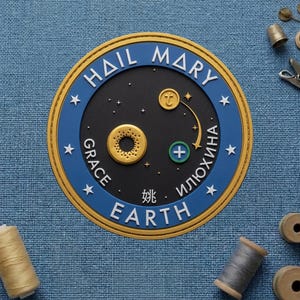 May include: A round, blue and gold emblem with the words "HAIL MARY" and "EARTH" in white. The emblem has a black center with gold accents and stars. The words "GRACE" and "ИЛЮХИНА" are also present.