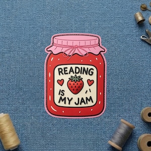 May include: A red strawberry jam jar sticker with a pink lid and a white label featuring the text READING IS MY JAM, a central strawberry illustration, and two small red hearts on either side of the strawberry, all outlined in pink.