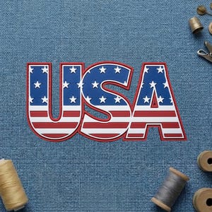May include: A dimensional patch featuring the letters USA in a bold, block font. The design incorporates the American flag pattern with a blue field containing white stars on the upper sections and horizontal red and white stripes below.