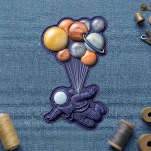 May include: A navy blue patch featuring an astronaut floating with planets. The planets are various colors, including yellow, orange, brown, and gray. The astronaut is wearing a spacesuit and has a white visor.
