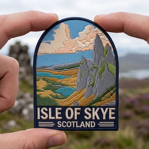 May include: An embroidered patch featuring a landscape of the Isle of Skye, Scotland. The design shows jagged grey mountains, green hills, and blue water under a sky with peach-colored clouds. The text ISLE OF SKYE SCOTLAND is at the bottom.