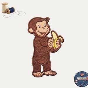 May include: Embroidered patch featuring a brown monkey holding a yellow banana. The monkey has a smiling expression. The patch is likely for clothing or accessories. Additional sewing supplies are in the background.