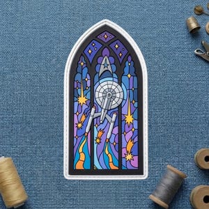 May include: A colorful patch featuring a stained-glass window design with a Star Trek theme. The image includes the Starship Enterprise, stars, and vibrant colors like blue, purple, orange, and yellow. The patch has a white border.