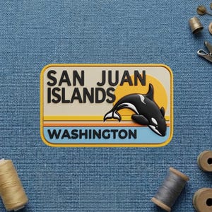 May include: A rectangular patch featuring the text SAN JUAN ISLANDS and WASHINGTON in black lettering. The design includes a black and white orca whale leaping in front of a yellow sun and horizontal stripes in orange, yellow, and light blue colors.