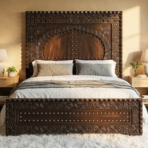 Puede incluir: Una cama de madera marrón oscuro, tallada intrincadamente, con cabecero a juego. La cama está hecha con ropa de cama blanca y almohadas grises. Dos mesitas de noche de madera con lámparas flanquean la cama. Una alfombra blanca y esponjosa está en el suelo.