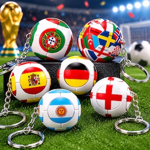 May include: A collection of six spherical keychains, each designed to resemble a soccer ball featuring various national flags including Portugal, Spain, Germany, Argentina, and England, attached to silver-toned metal key rings and chains.