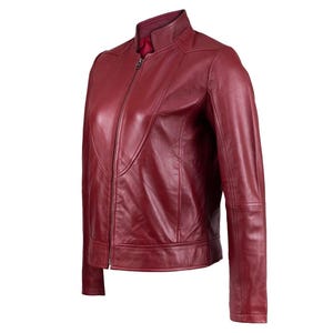 Puede incluir: Una chaqueta de cuero rojo oscuro con cuello alzado, cierre de cremallera frontal completo y mangas largas. La chaqueta tiene un acabado liso con detalles de costuras visibles en el pecho y los hombros, y un forro interior de color rojo s&oacute;lido.