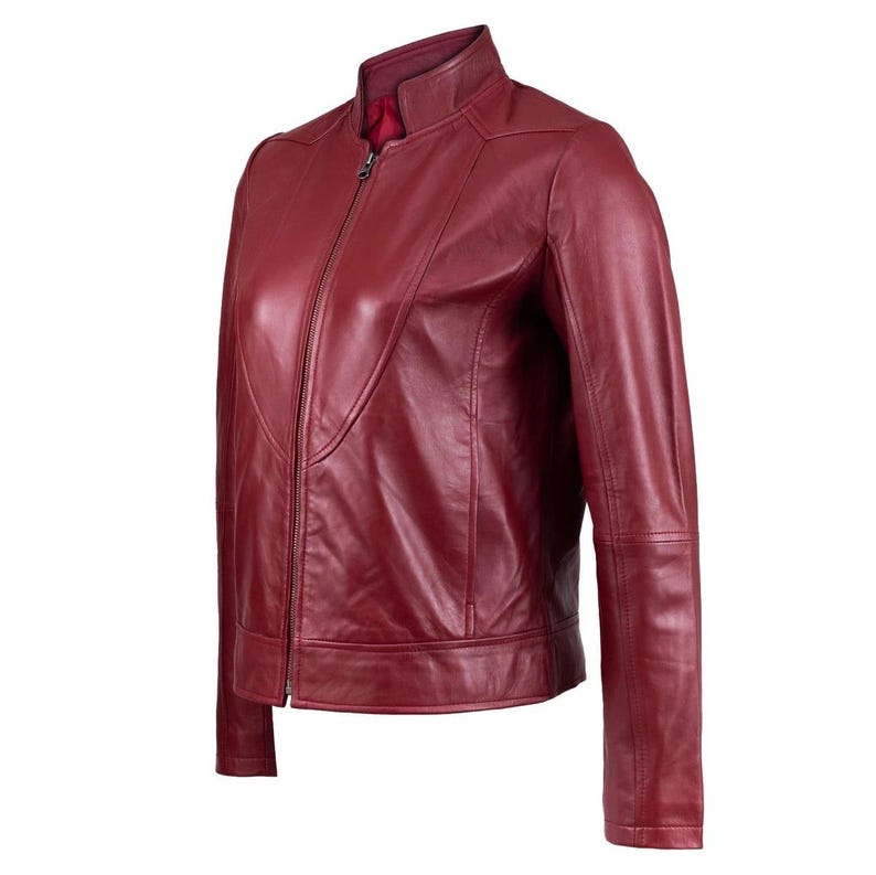 Puede incluir: Una chaqueta de cuero rojo oscuro con cuello alzado, cierre de cremallera frontal completo y mangas largas. La chaqueta tiene un acabado liso con detalles de costuras visibles en el pecho y los hombros, y un forro interior de color rojo s&oacute;lido.