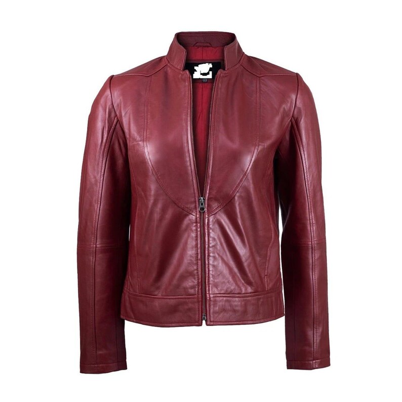 Puede incluir: Una chaqueta de cuero rojo oscuro con cuello alto, cremallera frontal completa y mangas largas. La chaqueta tiene un acabado liso con detalles de costuras visibles en el pecho y los hombros, y un forro interior de color rojo oscuro.