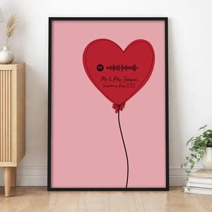 May include: A framed vertical wall art print featuring a light pink background and a large red heart-shaped balloon graphic. The balloon contains a black Spotify code, the text Mr & Mrs Johnson, and the date Valentine's Day 2025 in black script.