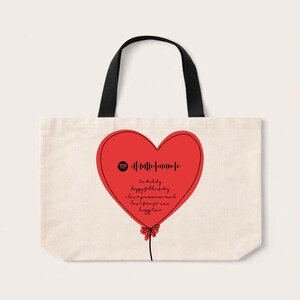 May include: A cream-coloured tote bag with black handles featuring a large red heart-shaped balloon graphic. Inside the heart is a black Spotify code, and the handwritten text: To daddy, happy fathers day, I love you sooooo much, love from jia xxx, huggy time.