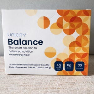 May include: A white box of Unicity Balance drink mix. The box features the word "Balance" in large blue letters. The box also states "The smart solution to balanced nutrition" and "Natural Orange Flavor". The box contains 30 stick packs.