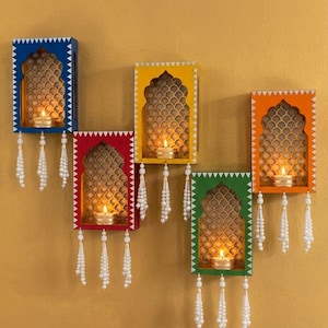 May include: Five colourful wall sconces, each with a candle. The sconces are blue, red, yellow, green, and orange. They feature a decorative cutout design and white beaded tassels hanging below. The image says 'Reference photo only'.