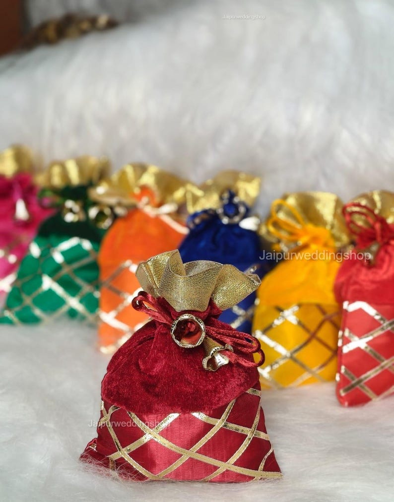 May include: A collection of colorful velvet pouches with gold accents. The pouches are in various colors, including red, orange, green, and blue. Each pouch has a gold drawstring and a gold diamond pattern.
