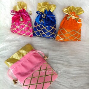May include: A collection of colorful velvet drawstring bags. The bags are in shades of pink, blue, and orange, with gold accents and a lattice design. Each bag has a gold-colored drawstring and a small bell charm.