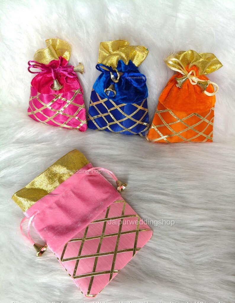 May include: A collection of colorful velvet drawstring bags. The bags are in shades of pink, blue, and orange, with gold accents and a lattice design. Each bag has a gold-colored drawstring and a small bell charm.