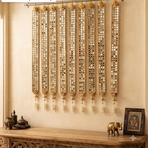 May include: Nine vertical wall hanging strips featuring a gold-toned fabric base densely decorated with small circular mirrors. Each strip is suspended from a metal rod by a gold hook and finished at the bottom with a decorative gold tassel.