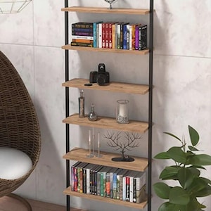 May include: A contemporary wall-mounted bookshelf with five wooden shelves and black metal supports. The shelves are filled with books, a camera, ornaments, and candles. A wire globe and a potted plant are also present.