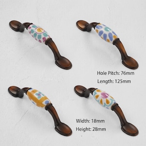 May include: Four arched cabinet handles with dark bronze metal ends and central ceramic sections featuring colorful floral patterns. The handles have a hole pitch of 76mm, a length of 125mm, a width of 18mm, and a height of 28mm as indicated by text.
