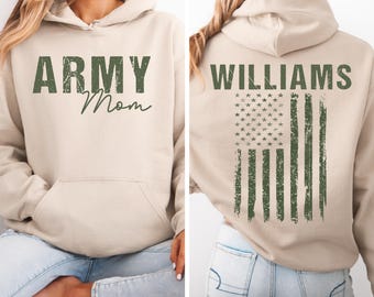 May include: A beige hoodie with the text "ARMY Mom" in green on the front. The back of the hoodie features the name "WILLIAMS" and a distressed American flag design in green.